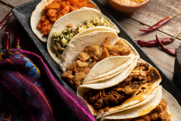 Different types of tacos also called guisados on a wooden background. Mexican food stock photo