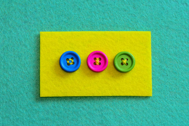 Different ways to sew buttons to felt by hand aesthetic. Felt piece with bright buttons isolated on felt background. Stitch buttons for sewing projects with colorful thread. Flat lay sewing. Top view. Sewing basics for beginners stock photo