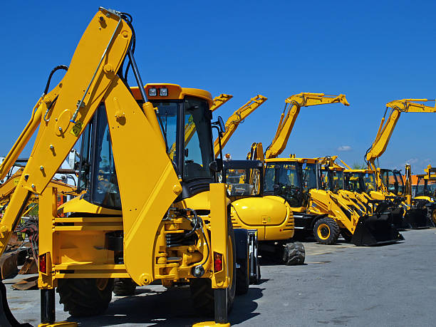 Diggers in a Row on Industrial Parking Lot New, shiny and modern yellow excavator machines waiting on buyers.  medium group of objects stock pictures, royalty-free photos & images