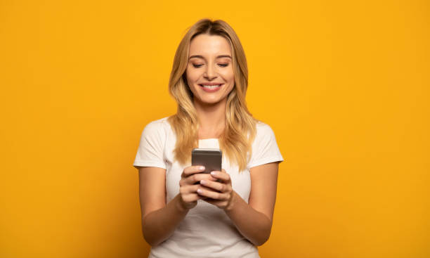 Digital was. Close-up photo of a happy woman in a casual outfit, who is texting to someone on her smartphone. using phone photos stock pictures, royalty-free photos & images