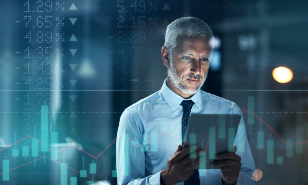 Digitally enhanced shot of a handsome businessman using a tablet superimposed over a graph showing the ups and downs of the stock market stock photo
