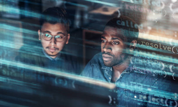 Digitally enhanced shot of two handsome businessmen working in the office superimposed over multiple lines of computer code stock photo
