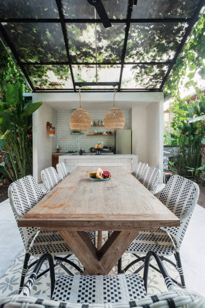Dining room table and chairs on open kitchen Vertical photo of glass roof over dining room table and chairs on modern open kitchen with greenery on background greenhouse table stock pictures, royalty-free photos & images