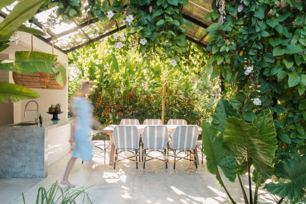 Dining room table and chairs on open kitchen Blurred woman walking near dining room table and chairs at open kitchen against green plants on background greenhouse table stock pictures, royalty-free photos & images