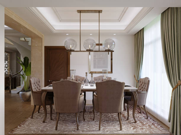Dining table for six with soft brown chairs and a wooden server table and glass pendant light. stock photo