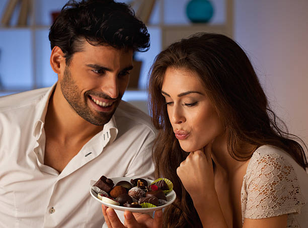Dinner Romantic couple having dinner at home. Man offering chocolate to woman. couple eating chocolate stock pictures, royalty-free photos & images