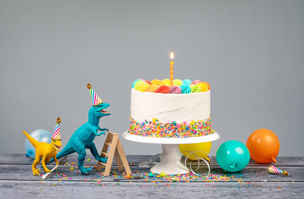 Dinosaur Birthday Party Hungry toy dinosaurs wearing hats and holding forks next to a birthday Cake on a gray background humorous happy birthday images stock pictures, royalty-free photos & images