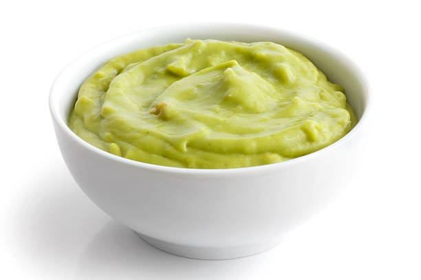 Dip for tortilla chips. Round white bowl of tortilla guacamole dip isolated in perspective. guacamole stock pictures, royalty-free photos & images