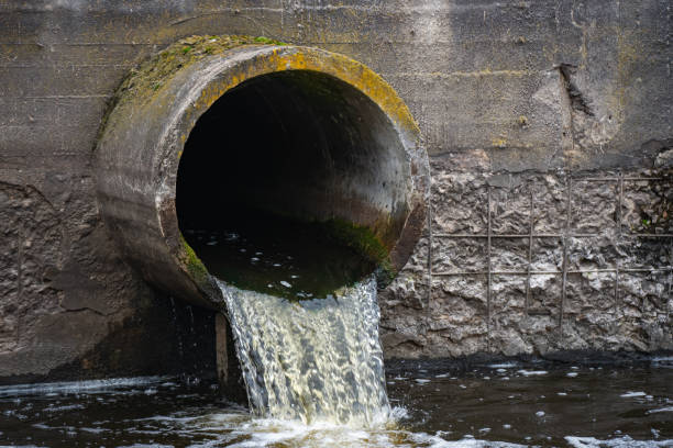Dirty water flows from the pipe into the river, environmental pollution. Sewerage, treatment facilities stock photo