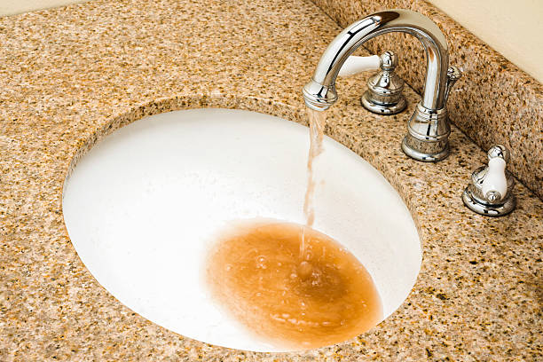 Dirty water pouring out of Vanity faucet into sink bowl Looking down on brown contaminated dirty water pouring out of a chrome goose neck faucet into a white porcelain sink bowl in a granite vanity top unhygienic stock pictures, royalty-free photos & images