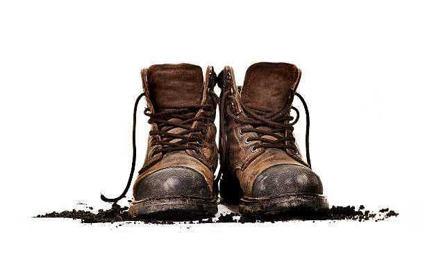 Dirty work boots isolated Dirty old work boots on white with dirt boot stock pictures, royalty-free photos & images