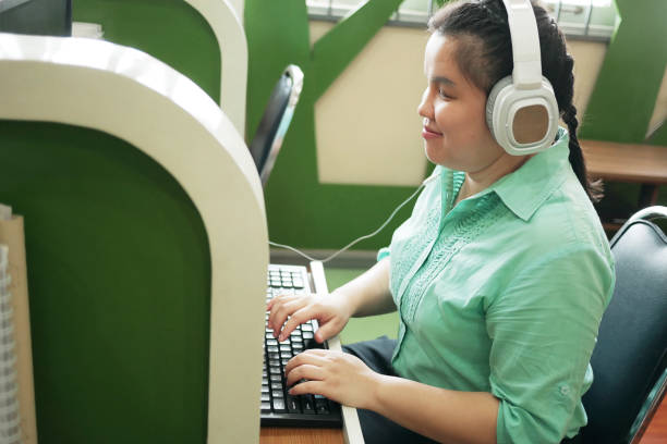 discapacidad joven ciego mujer feliz en auriculares escribiendo en el teclado de la computadora trabajando en la oficina creativa del lugar de trabajo. - ceguera fotografías e imágenes de stock