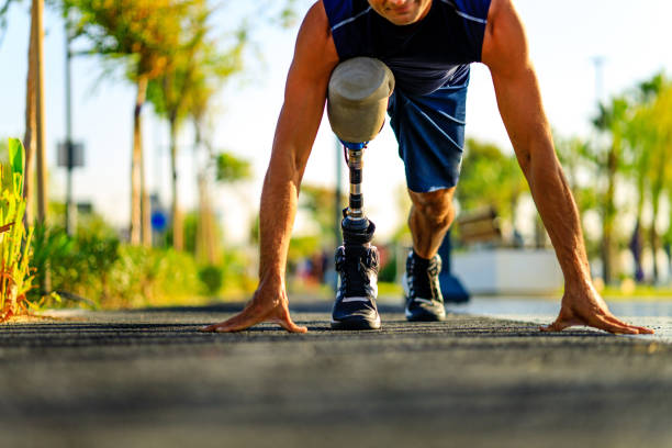 disabled athlete man with prosthetic leg starting to run at the beach on a treadmill outdoors at sunset stock photo