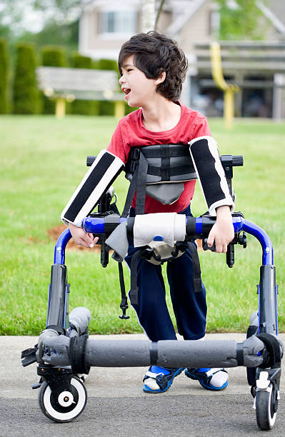 Disabled boy in walker by park stock photo