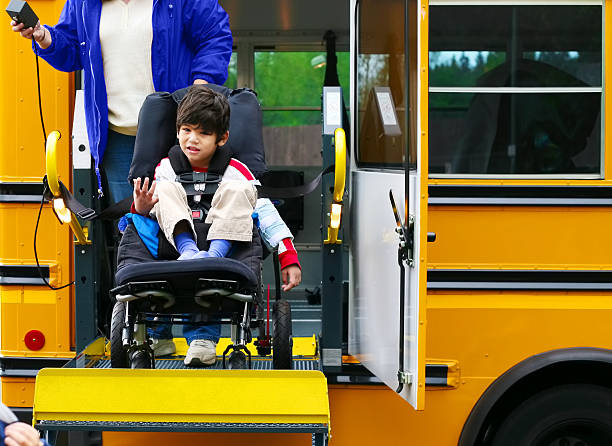 Disabled five year old boy using a wheelchairbus lift stock photo