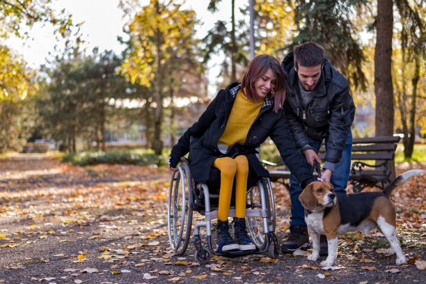 Disabled girl with boyfriend playing with dog in the park stock photo
