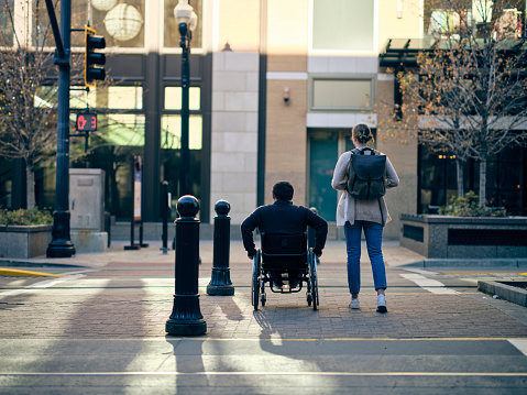 A man in a wheelchair with a young woman in a downtown area.