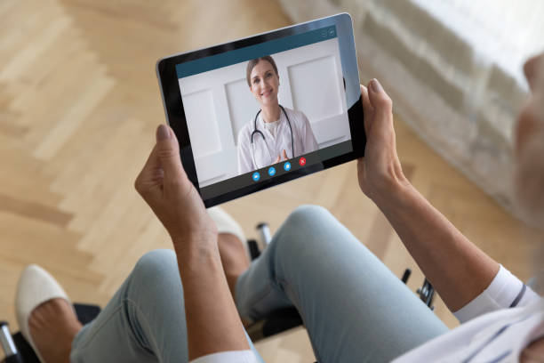 mujer mayor discapacitada tiene consulta de tableta en línea con el médico - nurse talking to camera fotografías e imágenes de stock