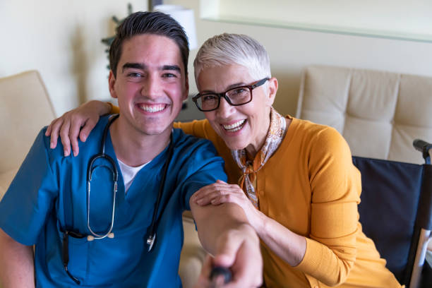 una mujer mayor discapacitada está tomando una foto selfie con un médico joven. - nurse talking to camera fotografías e imágenes de stock