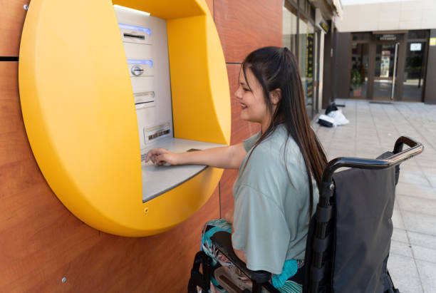 disabled young woman in wheelchair with ATM stock photo