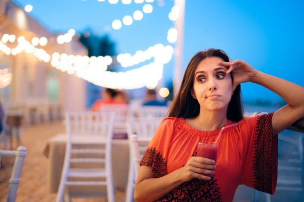 besviken uttråkad kvinna som håller en cocktail på en dag - boring date bildbanksfoton och bilder