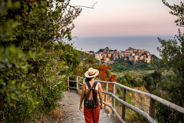 Discovering Italy. Female tourist walking towards Corniglia village, Beautiful town in Cinque Terre coast beach hike stock pictures, royalty-free photos & images