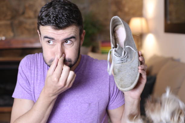 Disgusted man holding stinky shoe stock photo