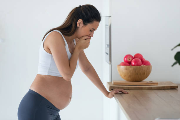 Disgusted pregnant young woman suffering with nausea in morning at home. stock photo