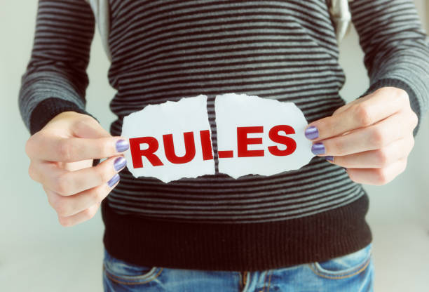 Disobedient young woman tears up the rules Woman's hands tearing up the word Rules. rule breaker stock pictures, royalty-free photos & images