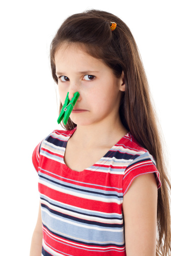 Displeased girl with clothespins on his nose, isolated on white