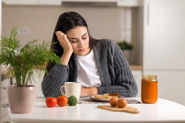 Displeased young woman doesn't want to eat her breakfast stock photo