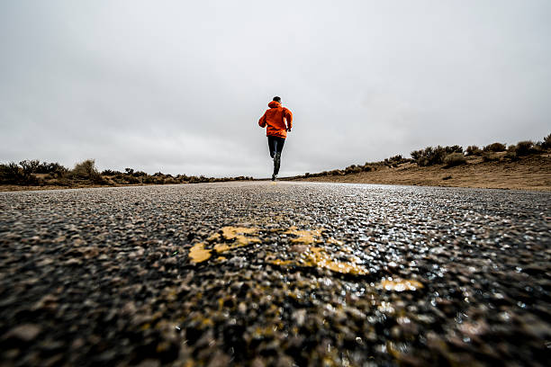 distance A man running on a paved road marathon stock pictures, royalty-free photos & images