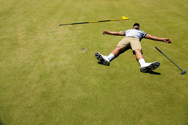 Distraught golfer lying on putting green. stock photo