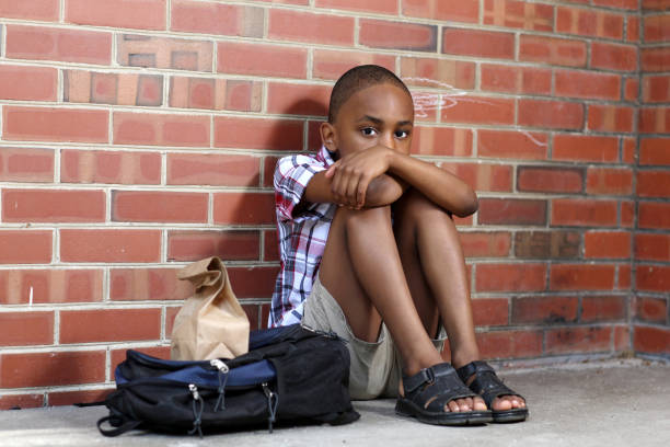 Distraught litttle boy sits alone at school. stock photo