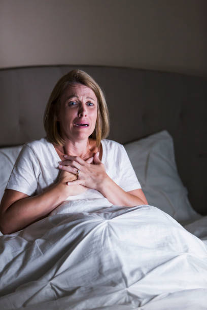 förtvivlad kvinna på natten i sängen - medelålders kvinna bröstsmärtor bildbanksfoton och bilder