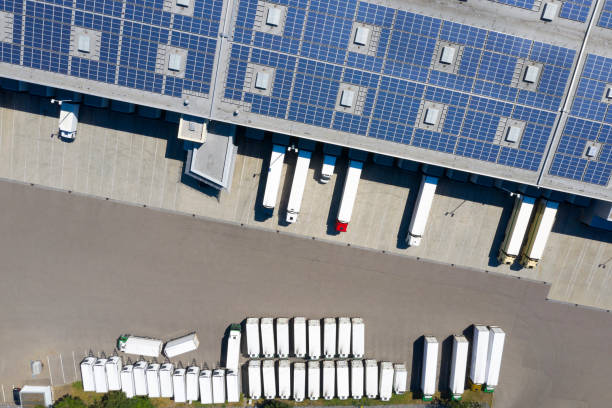 distributiemagazijn met zonnepanelen en vrachtwagens van bovenaf - zonnepanelen warehouse stockfoto's en -beelden