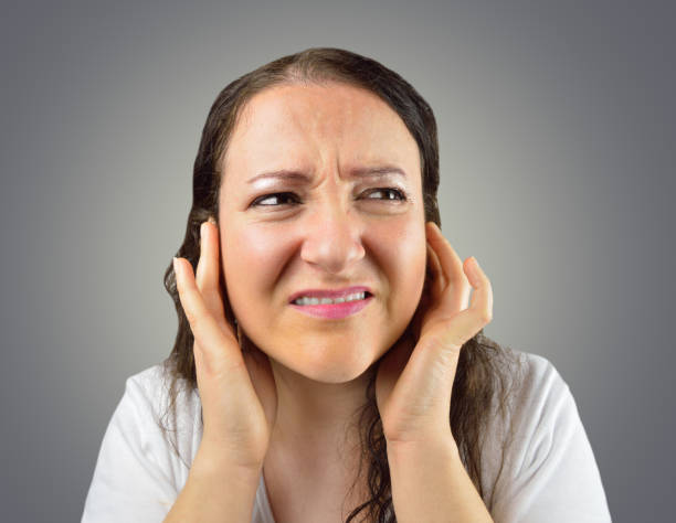 Disturbed By Noise woman covering her ears with her hands isolated on a gray background Fingers in Ears stock pictures, royalty-free photos & images