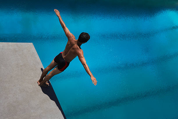 Diver standing on diving board  diving into water stock pictures, royalty-free photos & images