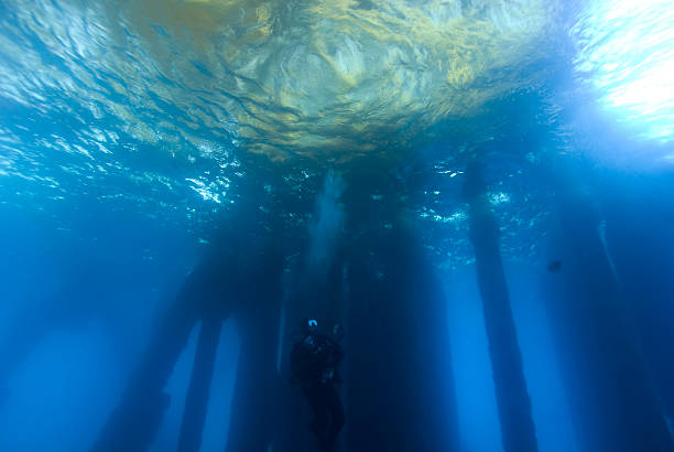 Diver Underwater Scuba Diving at Oil Rig Platform stock photo