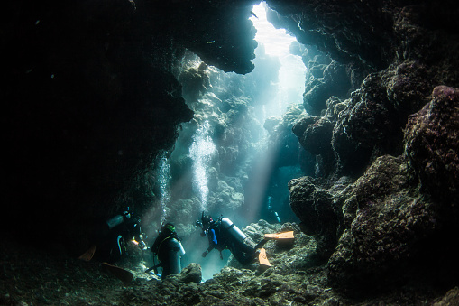 Scuba divers in a clear under water cave by the Kerama islands of Okinawa.