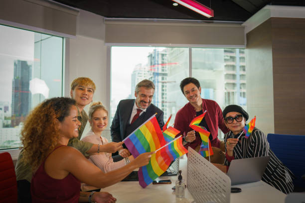 ビジネスの人々の多様なグループ (男性, 女性, ゲイ, トランスジェンダー, レズビアン, アジア人, 白人, アフリカ系アメリカ人, lgbtq) チームワークとして一緒に働くビジネスオフィスで手に虹 - lgbtqiaの文化 ストックフォトと画像