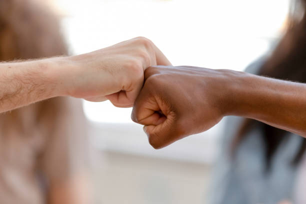 Diverse male hands giving fist bump, close up view Diverse male hands giving fist bump, two african american and caucasian men greeting as business partnership, multiracial people friends culture, power trust respect support concept, close up view high five stock pictures, royalty-free photos & images