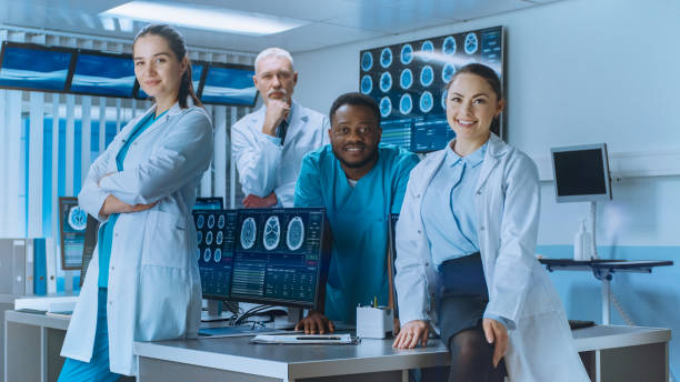 Diverse Team of Medical Scientist Posing with Crossed Arms in the High-Tech Laboratory. Brain Sceince / Neurology Center Research Lab with Multiple Dispalys Showing CT / MRI Scan Images. Diverse Team of Medical Scientist Posing with Crossed Arms in the High-Tech Laboratory. Brain Sceince / Neurology Center Research Lab with Multiple Dispalys Showing CT / MRI Scan Images. neurologist stock pictures, royalty-free photos & images