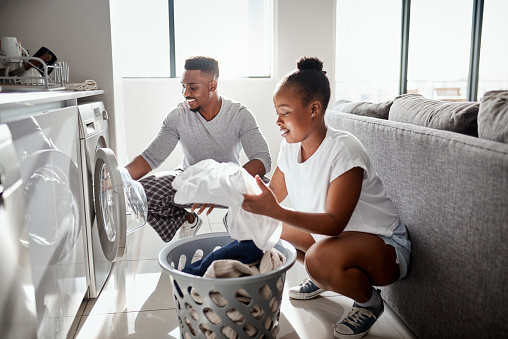 Shot of a happy young couple doing laundry together at home