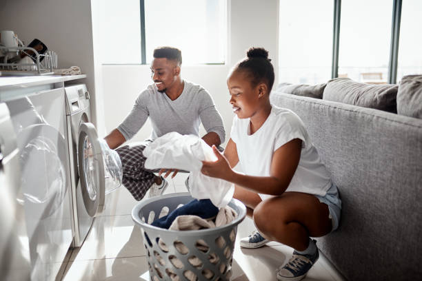 Division of labour isn't just for the workplace Shot of a happy young couple doing laundry together at home dryer photos stock pictures, royalty-free photos & images