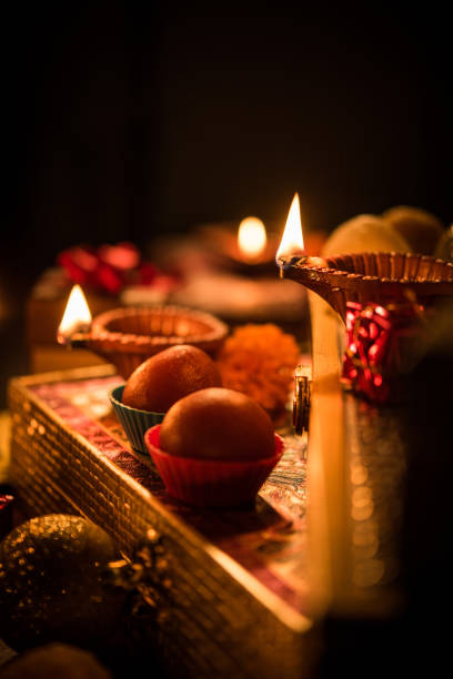 Diwali diya or lighting in the night with gifts, flowers over moody background. Selective focus Diwali diya or lighting in the night with gifts, flowers over moody background. Selective focus mithai stock pictures, royalty-free photos & images