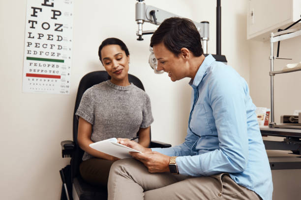 Do you have any health issues in your family? Shot of a young woman having an eye exam by an optometrist eye doctor stock pictures, royalty-free photos & images
