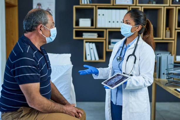 Do you have any questions so far? Shot of a doctor using a digital tablet to discuss a brain scan with a senior patient neurologist stock pictures, royalty-free photos & images