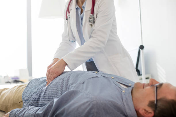 Doctor analyzing abdomen of patient in examination room at hospital stock photo