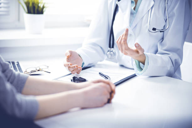 Doctor and  female patient sitting at the desk and talking  in clinic near window. Medicine and health care concept. Green is main color Close up of doctor and  patient  sitting at the desk near the window in hospital visit stock pictures, royalty-free photos & images